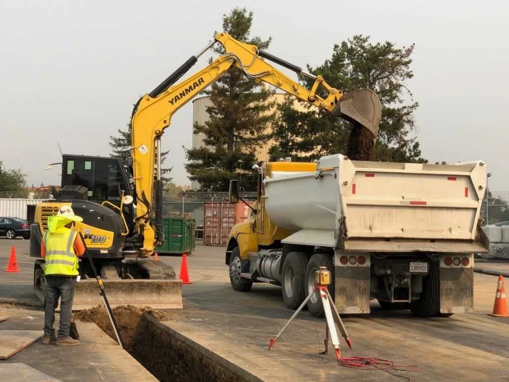 Excavator loading excavated soil into dump truck at construction site
