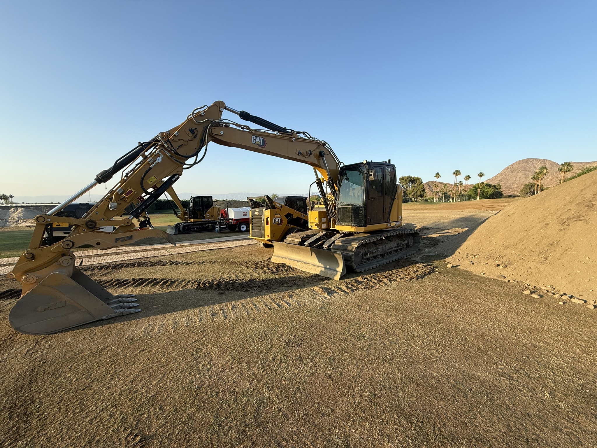 Yellow CAT excavator on graded dirt site next to earth materials, demonstrating and heavy equipment work.